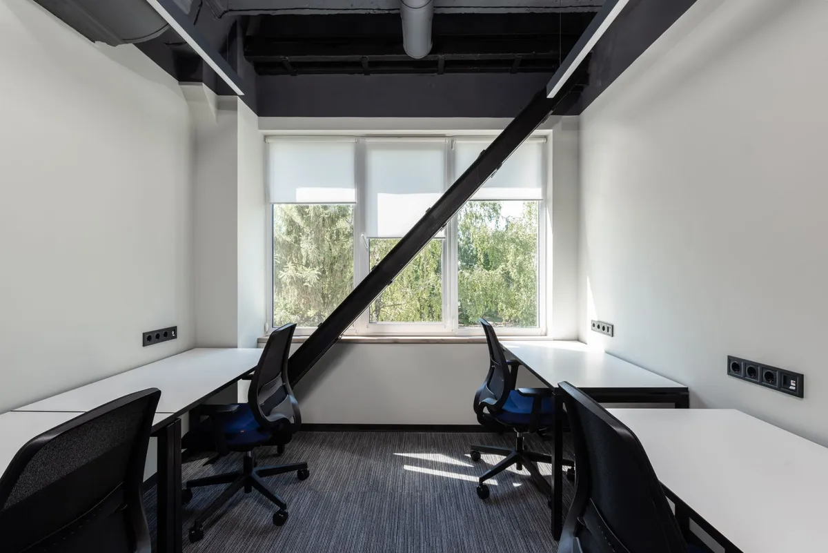 Light-filled office with workstations, carpet flooring and exposed ceiling services