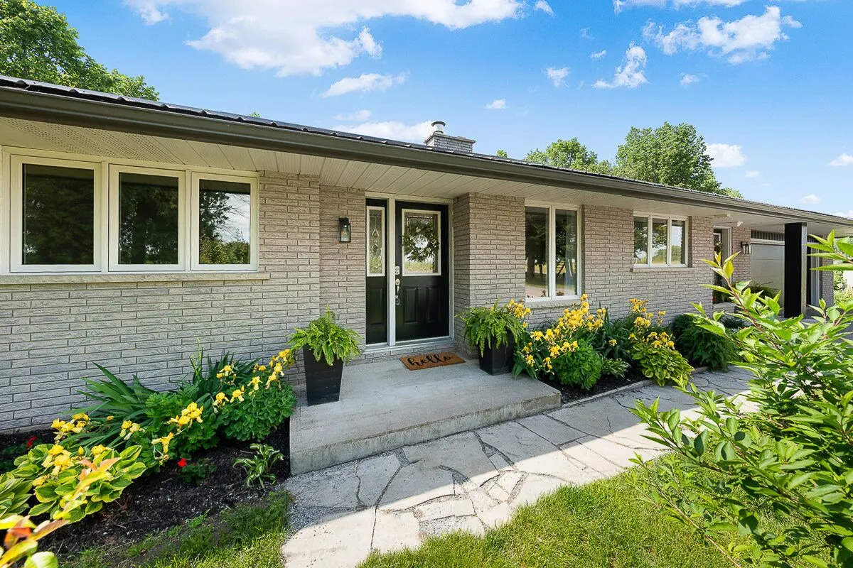 Front entry of a brick bungalow with landscaped gardens and stone walkway