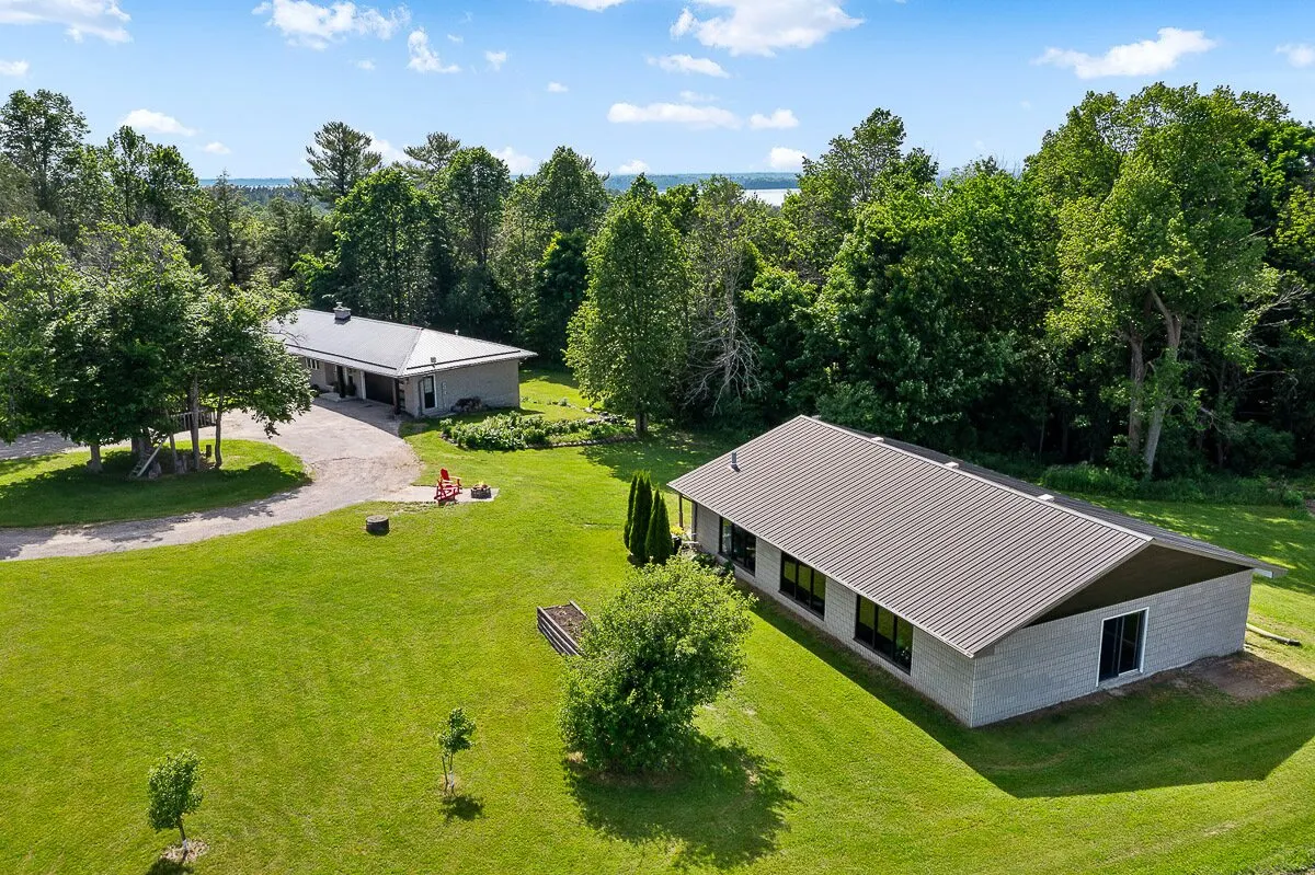 Aerial view of a country property with metal roofs on the house and outbuilding